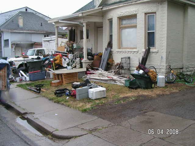 A white brick house with trash filling the front yard.